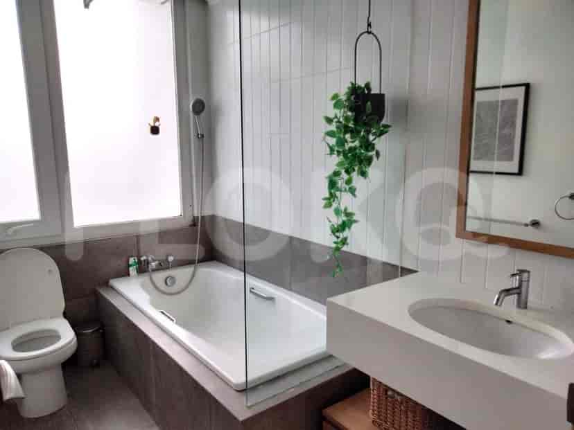 Kamar mandi dengan bak mandi, pancuran, dan tanaman gantung.