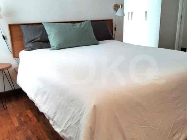 Kamar tidur dengan tempat tidur, lampu, dan papan kepala kayu.