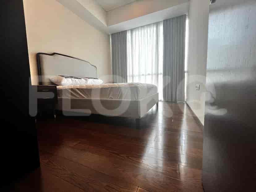 Bedroom with a bed, wooden flooring, and a view through the curtains.