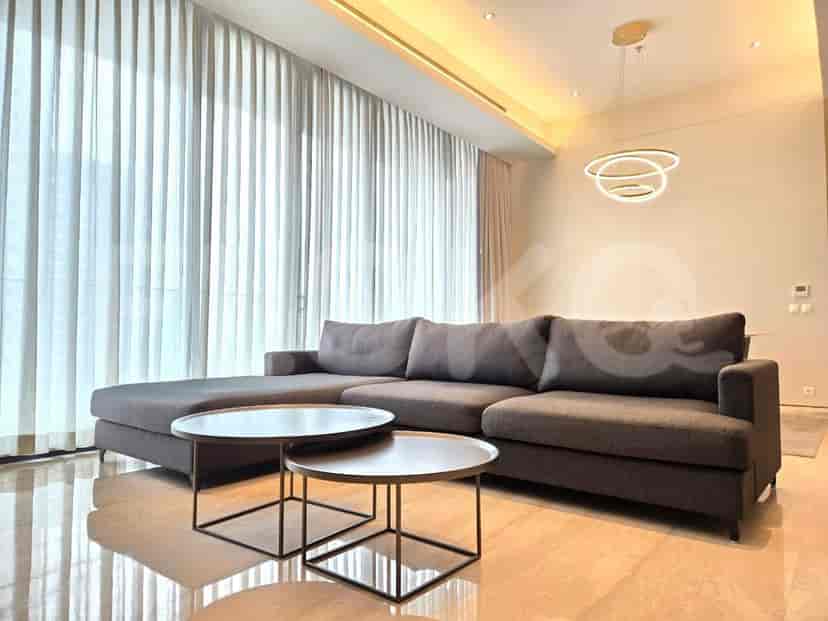 A modern living room with an L-shaped grey sofa, two round coffee tables, and a large window.