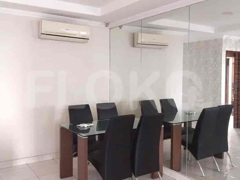 Dining area with a glass table and six black chairs.