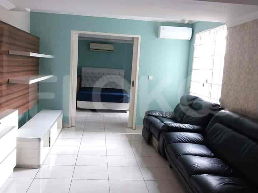 Living room with a black leather sofa, white storage, and a view into a bedroom.