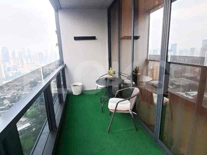Balkon dengan meja kecil dan kursi, menghadap pemandangan kota.