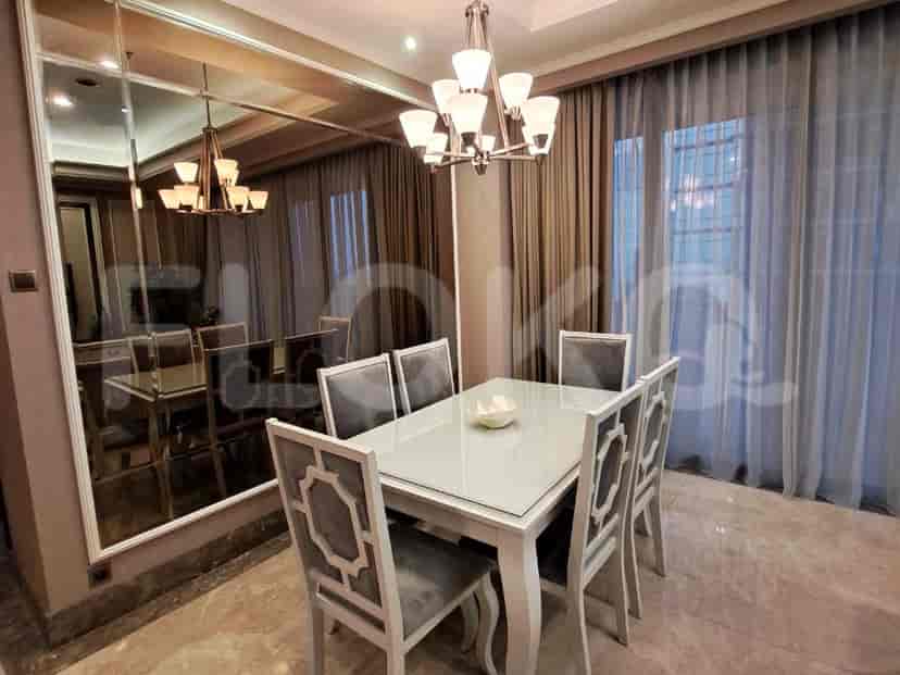 Area makan yang elegan dengan meja putih, kursi yang serasi, dan cermin besar yang meningkatkan keluasan ruangan.