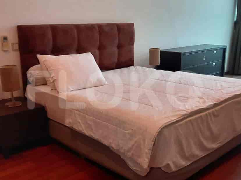 A bedroom featuring a bed with a burgundy headboard, bedside lamps, and a chest of drawers.