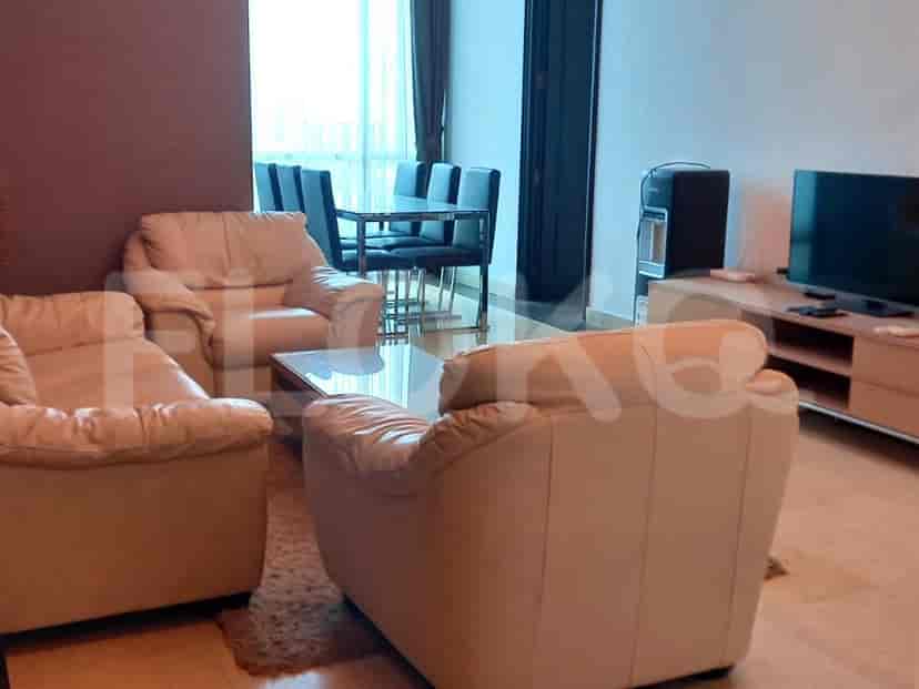 Living room with cream-colored leather armchairs, glass coffee table, and dining area.