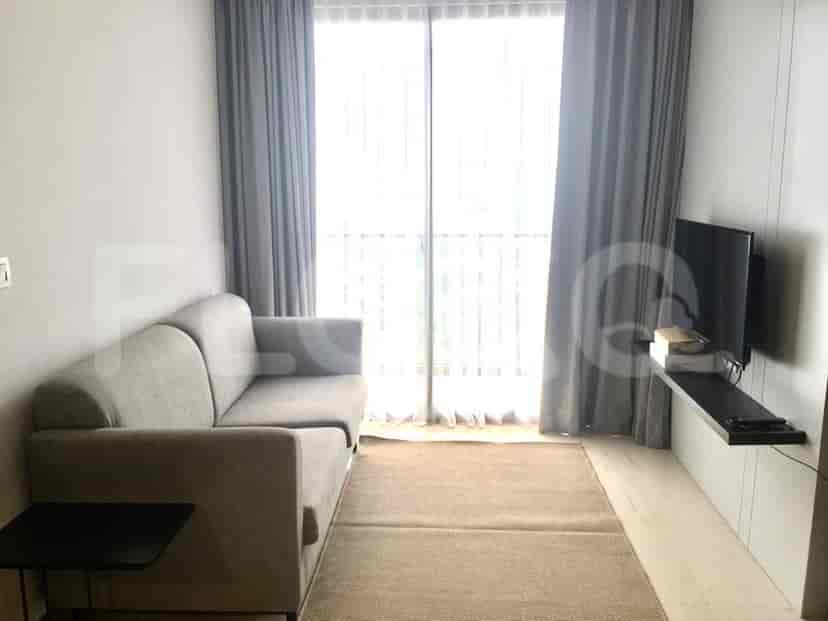 A cozy living room with a grey L-shaped sofa, a TV, and sheer curtains over a large window.