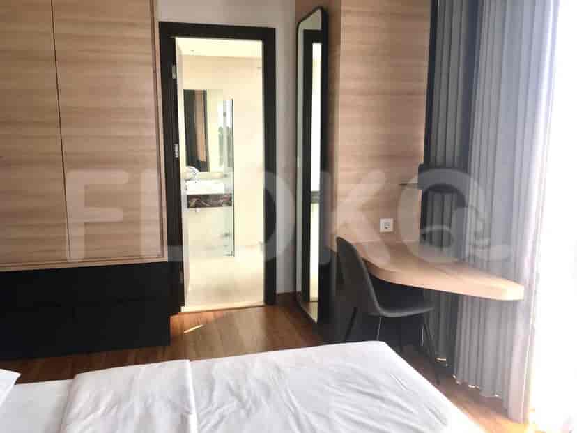 A bedroom with a desk, chair, bed, and a view into the bathroom.
