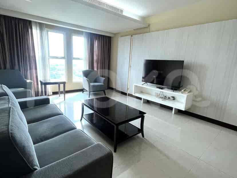 A modern living room with a grey sofa, TV, and large windows.