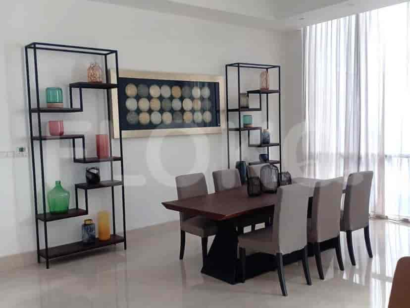 A dining area with a dark wooden table, chairs, and shelving units.