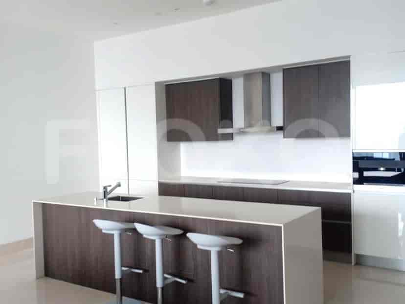 A kitchen with an island, stools, and overhead cabinets.