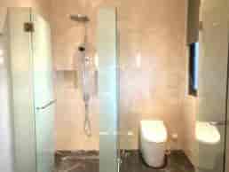 Modern bathroom with a shower stall, white toilet and marble floors.
