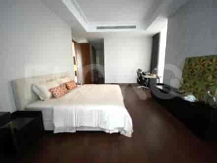 Spacious bedroom with a bed, workspace, and a modern, uncluttered design.