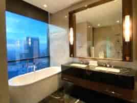 Luxurious bathroom with a bathtub, vanity and city views.