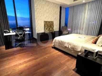 Bedroom with wooden flooring, desk, and city views from large windows.