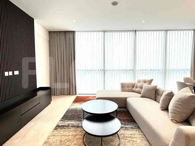 Spacious living room with an L-shaped sofa, black coffee tables, and large windows.