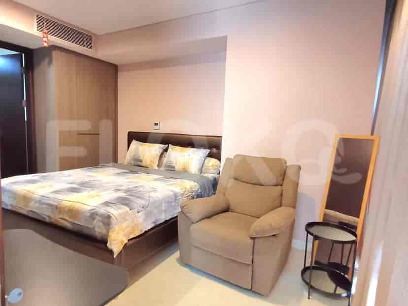 A bedroom with a double bed, armchair, and a full-length mirror.