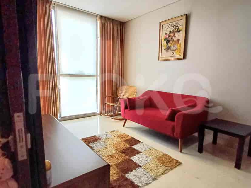 A living room with a red sofa, rug, and a view through a large window.