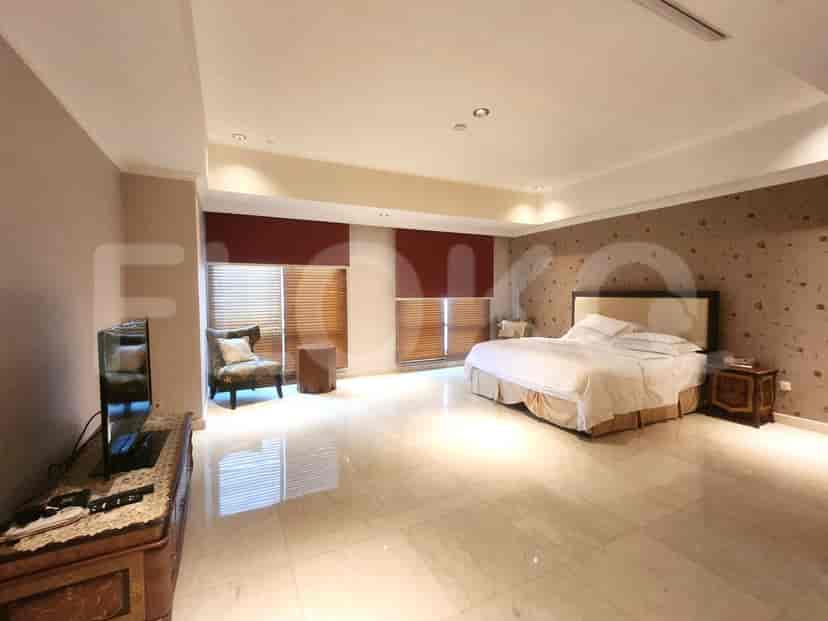 A bedroom with a queen bed, chair, TV, and dresser.