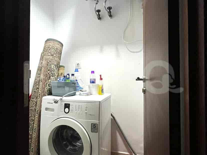 Laundry room with a washing machine, rug, and supplies.