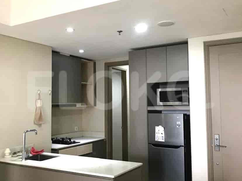 A modern kitchen with stainless steel appliances, cabinetry, and a doorway leading to another room.