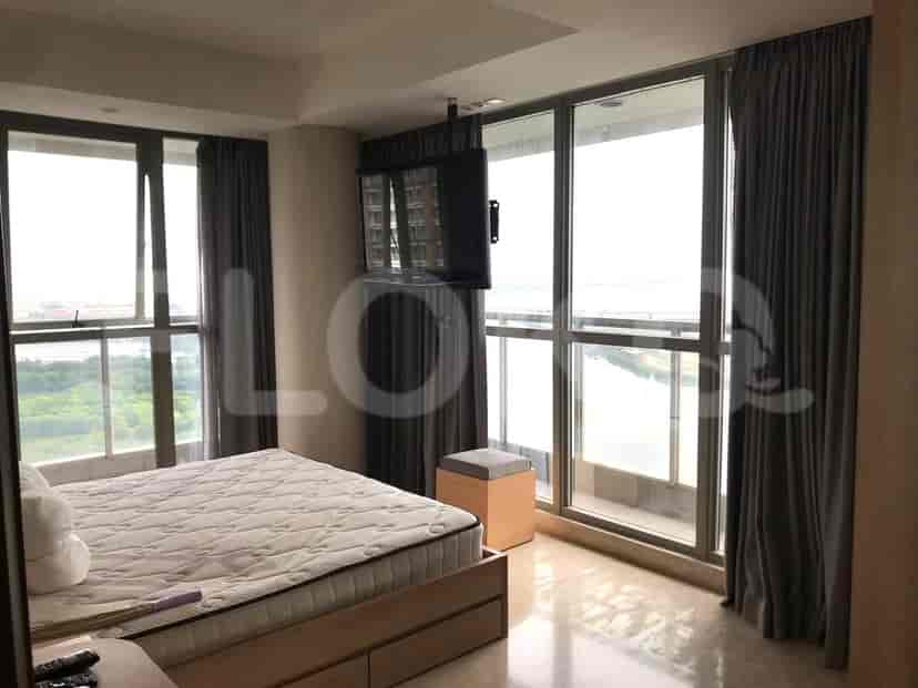 A bedroom with large windows, a bed, a television, and access to a balcony.