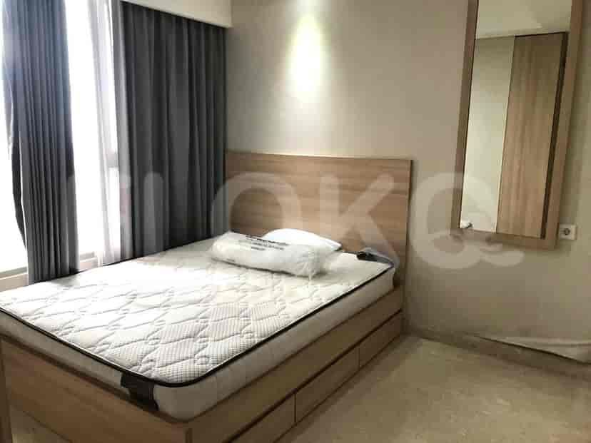 A bedroom featuring a wooden bed, a mattress with a pillow, a window with curtains, and a mirror.