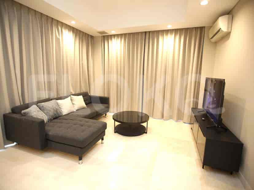 A modern living room with an L-shaped grey sofa, a TV, and large windows.