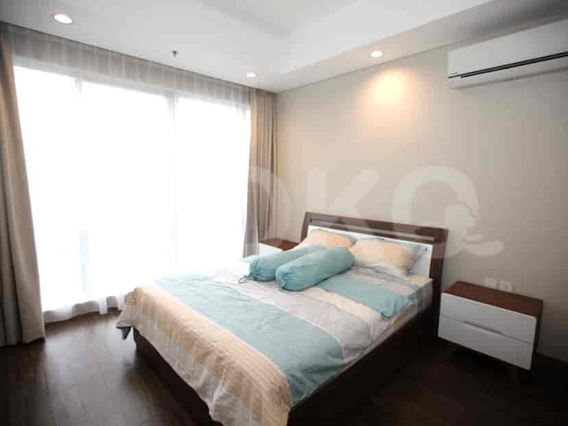A bright bedroom with a bed, large windows, and curtains.