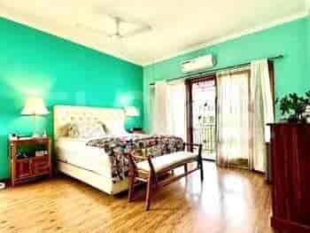 Bedroom with a queen bed, wooden furniture, and a balcony overlooking greenery.
