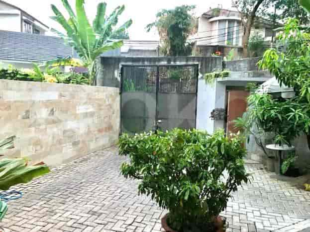 A view of a property's front entrance with a brick-paved driveway, a large black gate, and a garden.