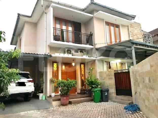 Exterior view of a two-story house with a combination of cream and beige exterior walls, wooden doors, and a small balcony.