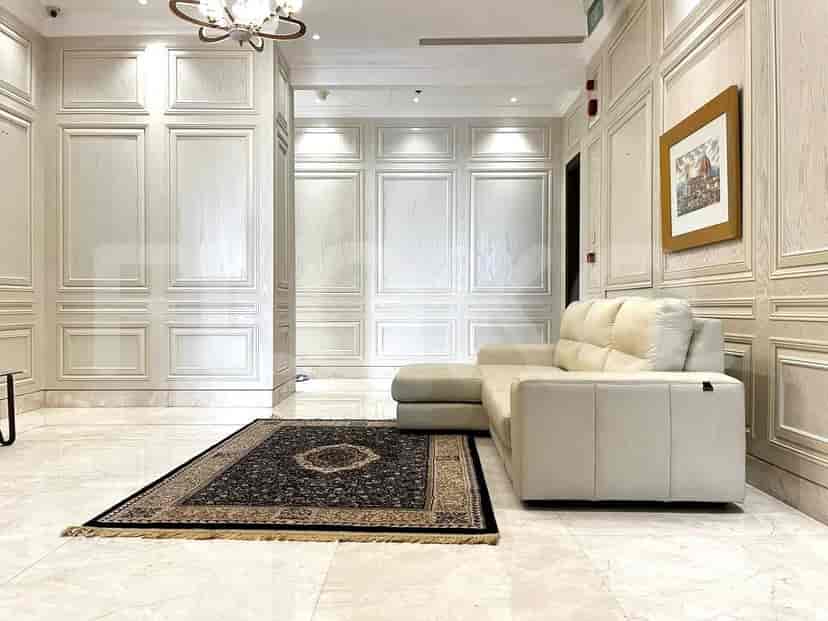 Sebuah lorong mewah dengan lantai marmer, dinding berpapan, dan sofa berwarna krem.