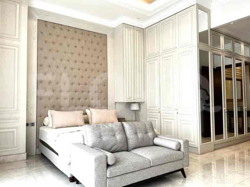Kamar tidur yang nyaman dengan sofa abu-abu, headboard berlapis, dan lemari cermin.