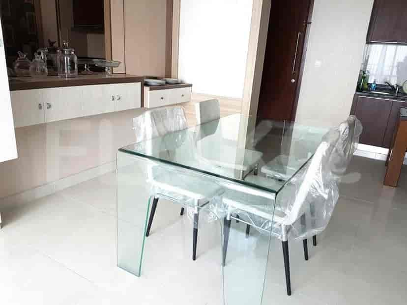 Dining area with glass table, chairs and kitchen in the background.