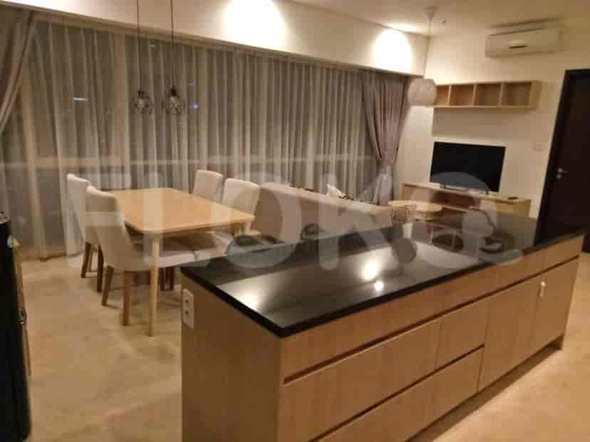 A modern living room with a dining area, kitchen island, and a sofa. Features include a large window with curtains, and a dining table with chairs.