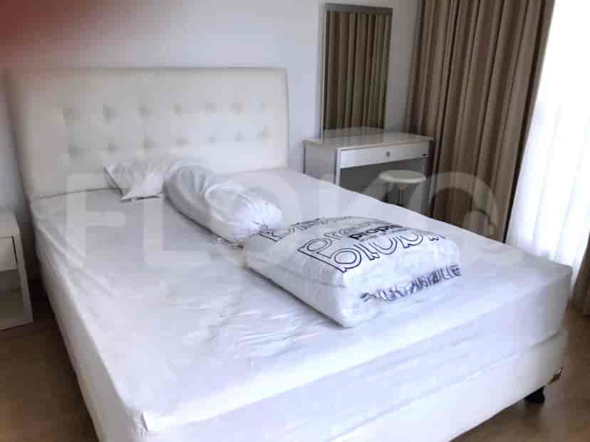 A bright bedroom with a white tufted headboard, comfortable bedding, and a vanity area.