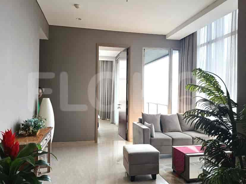 Spacious living room with a grey L-shaped sofa, a wooden side table, and large windows.