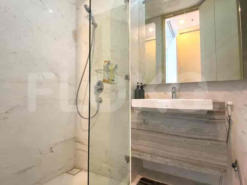 A modern bathroom with marble finish, a shower and sink.