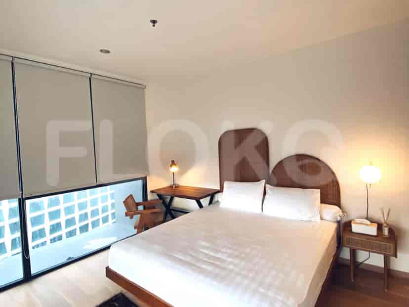 A second bedroom with a minimalist decor, featuring a bed and desk beside a window.