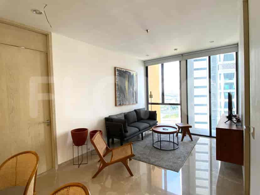 Living area with a dark grey sofa, a small round table, and city views through large windows.