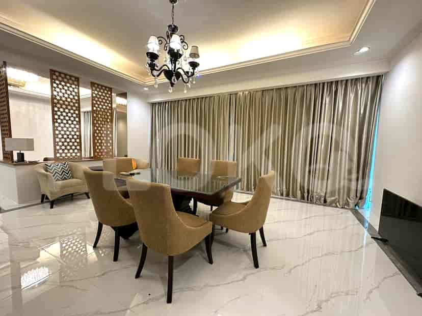 A dining area with a table, chairs, and a chandelier, featuring wooden panels.