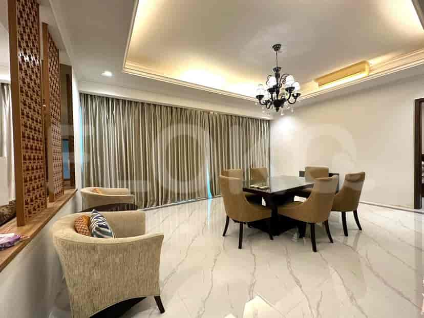A well-lit dining area with a dark wood dining table and chairs, and a decorative chandelier.