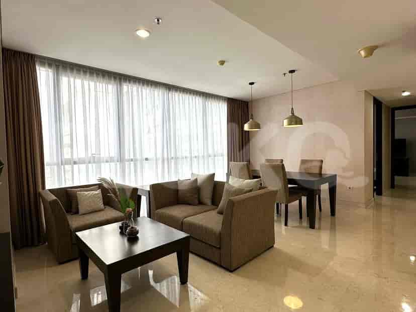 A combined living and dining area with modern furniture, featuring a sofa, dining table, and large windows.