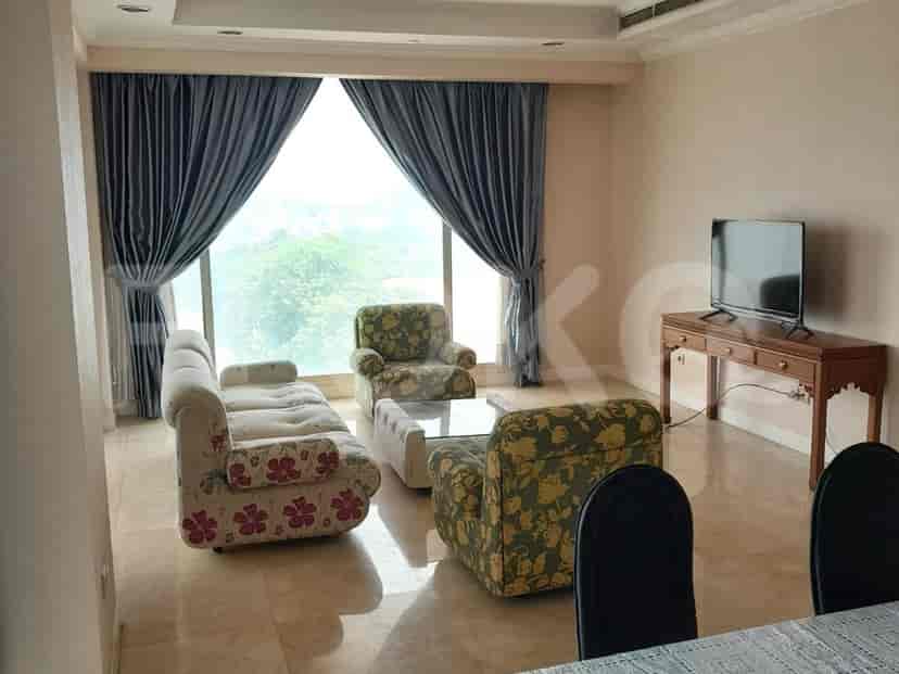 Living room with floral patterned furniture and large windows overlooking a city view.