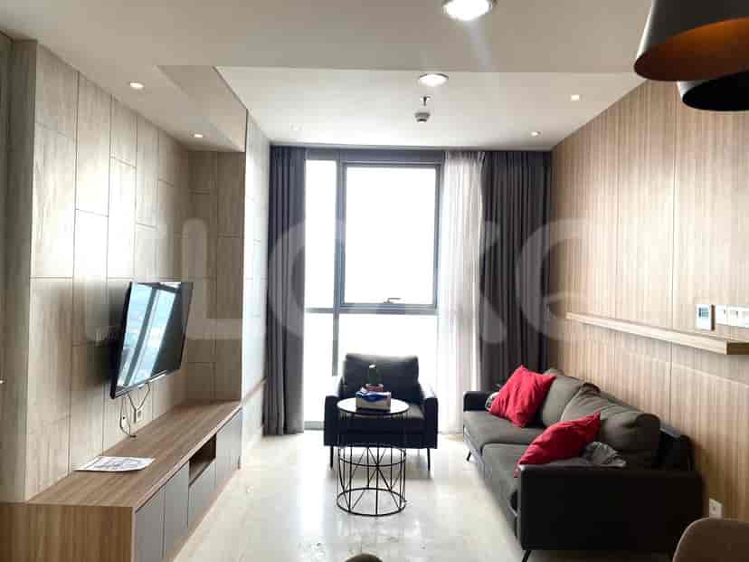 Modern living room with a grey sofa, TV, and large windows with curtains.