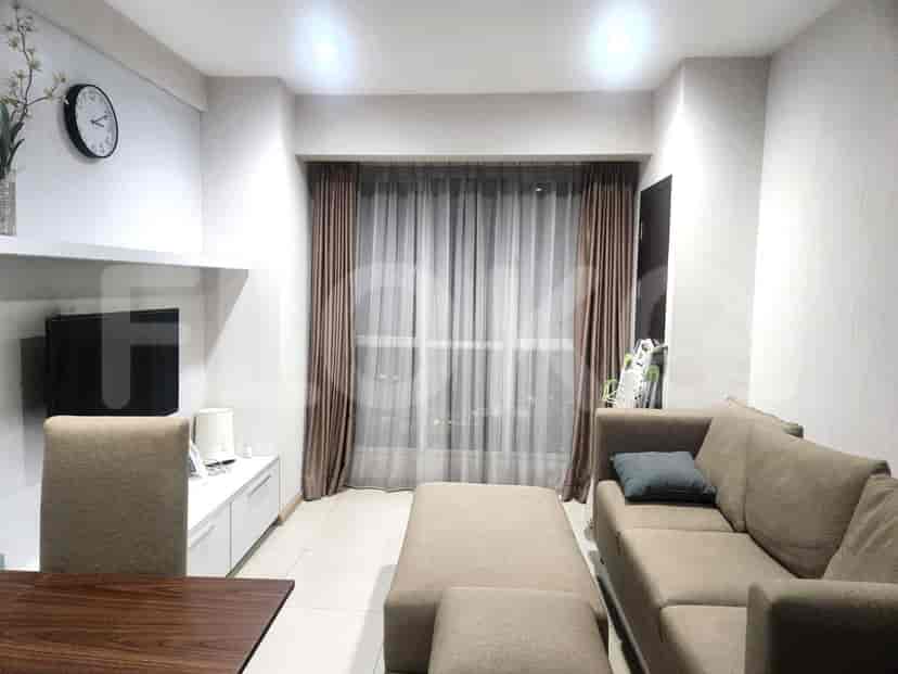 A living room featuring a modern design, with a sofa, TV, and large windows.