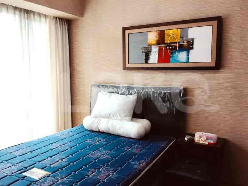 A well-lit bedroom with a single bed, a painting, and a nightstand.