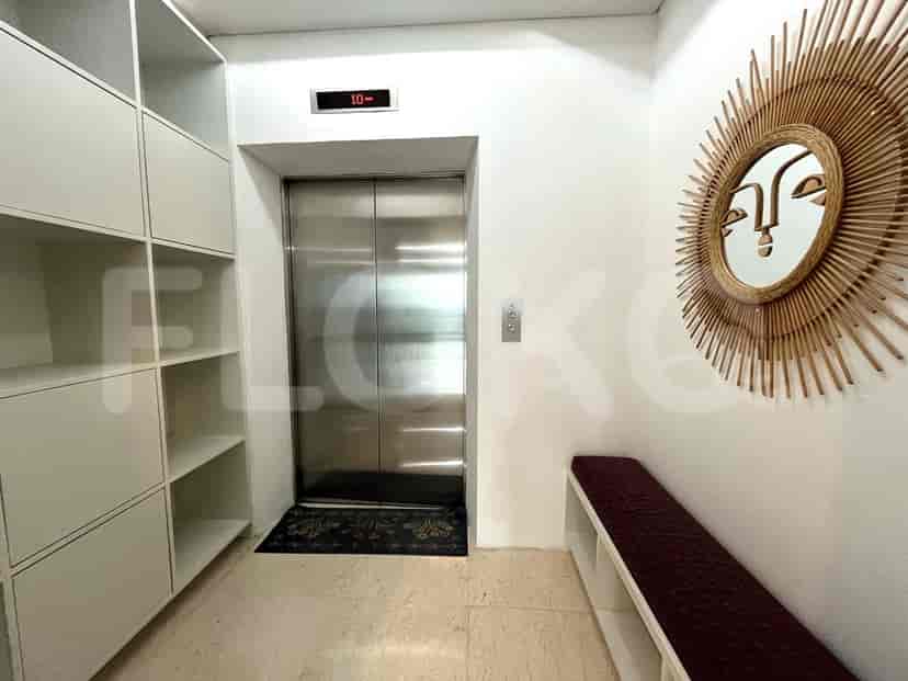 Entrance hall with an elevator, built-in shelving, and decorative mirror.