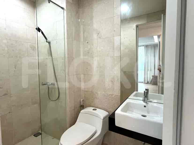 Bathroom with glass-enclosed shower, toilet, and marble walls.